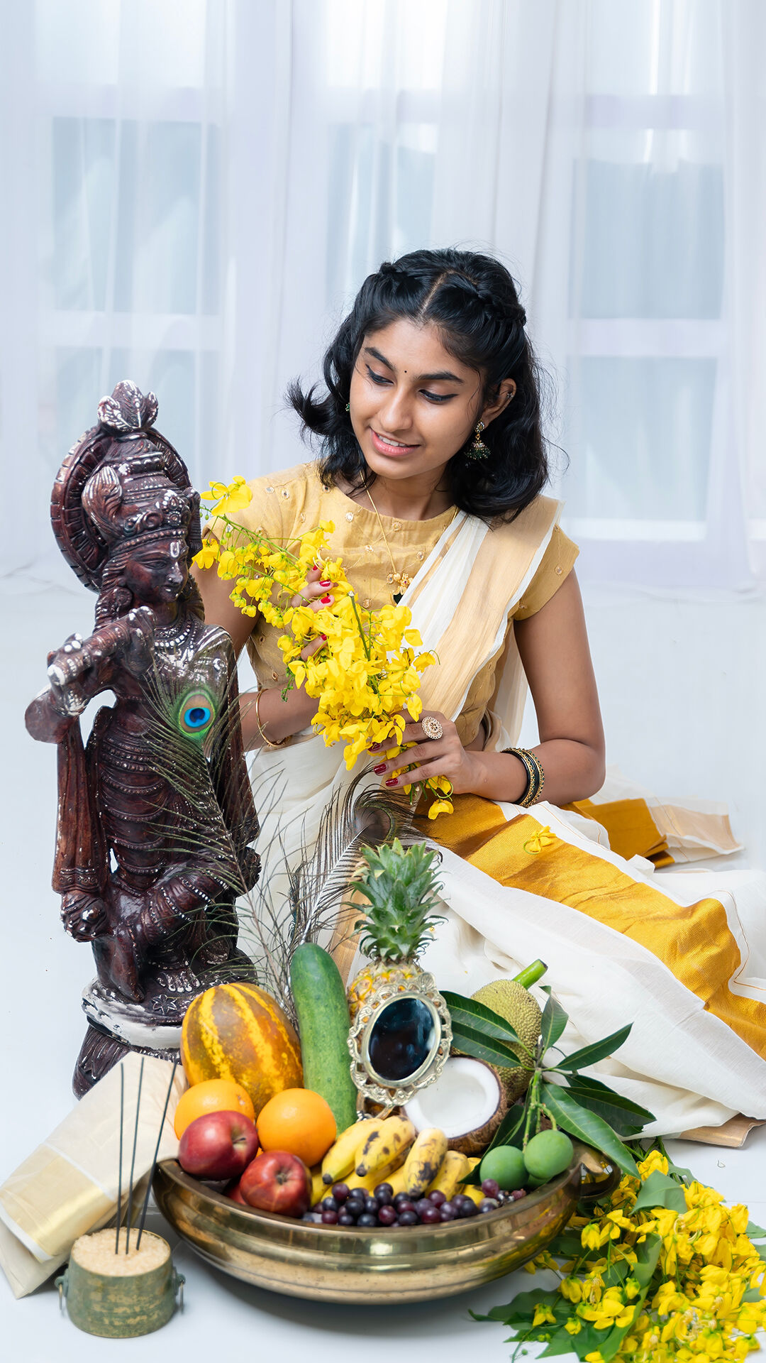 Young woman in traditional Kerala saree offering yellow flowers to a Krishna idol, with a plate of fruits and a peacock feather in front, during Janmashtami celebrations